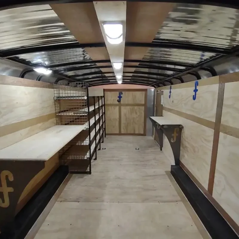 A long, narrow trailer filled with numerous shelves displaying various items